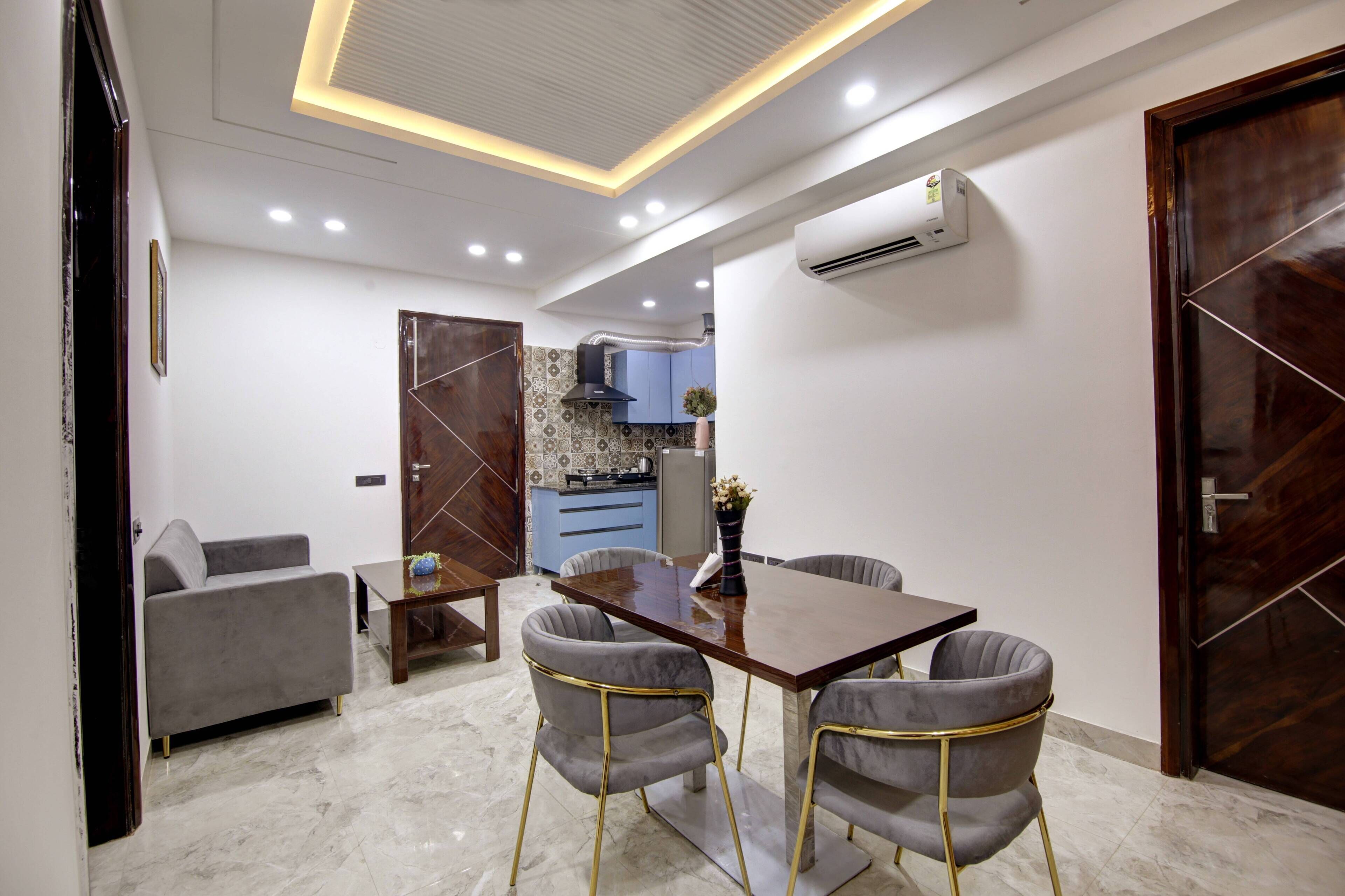 Un espacio habitable compacto con comedor, sofá y cocina al fondo.