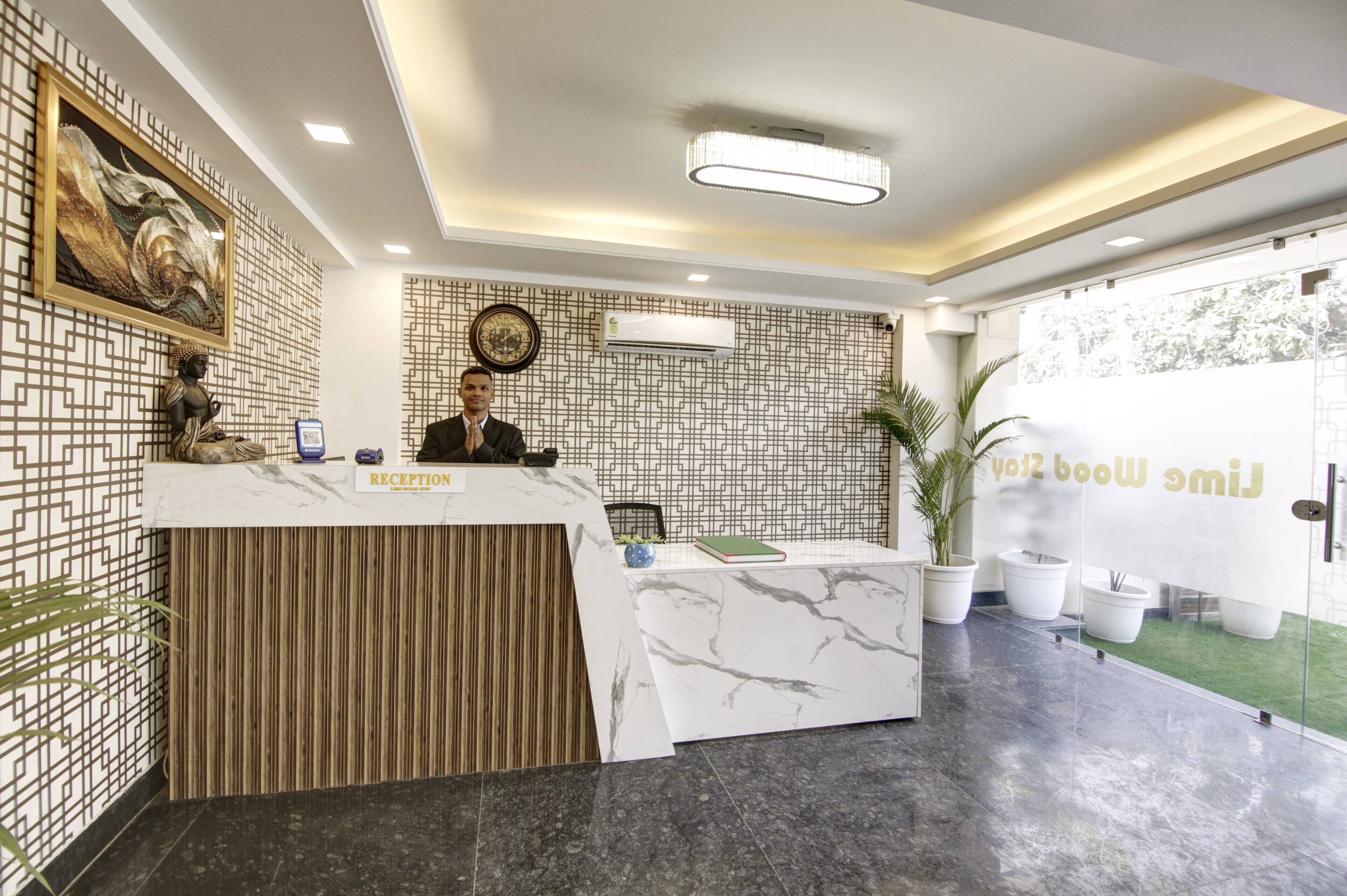 A reception desk with a marble top, a receptionist, and a wall with a geometric pattern.