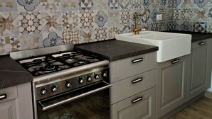 A kitchen with a gas stove, oven, and a sink with a faucet.