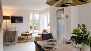 Una sala de estar moderna con comedor, sofá, televisor y un amplio ventanal.