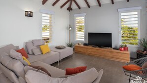 A modern living room with a sofa, TV, and potted plants.