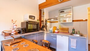 Une cuisine compacte équipée d’un four à micro-ondes, d’un grille-pain et d’une machine à café. Elle comprend un petit évier et un espace pour faire la vaisselle.