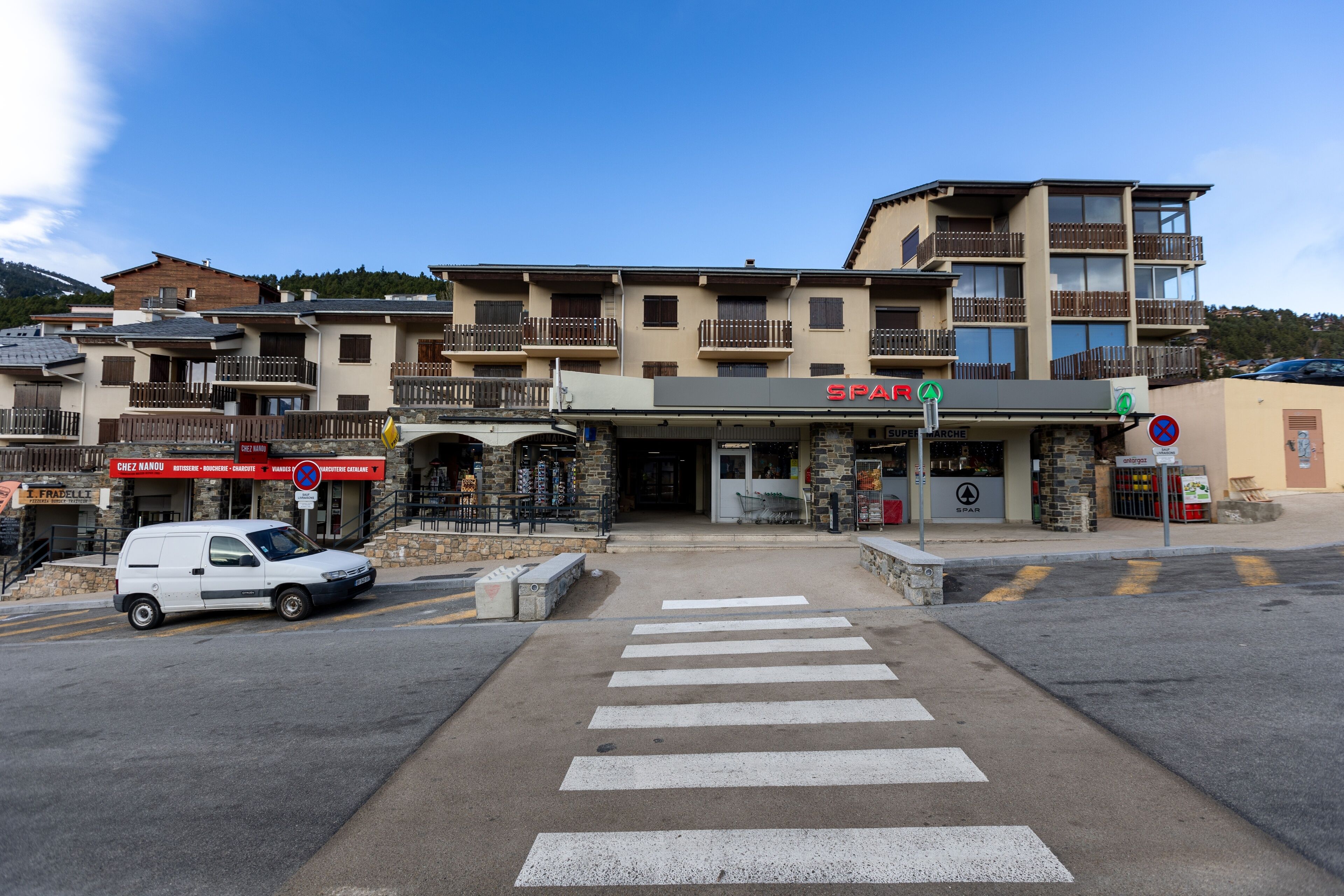 A multi-story building with a ground-level shop and a parking area.