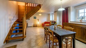 Una cocina amplia con una escalera de madera, una mesa de comedor con sillas y un sofá rojo al fondo.