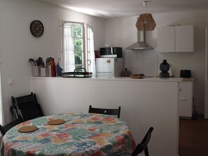 A kitchen with a dining area, a clock, and a window with curtains. - Cantebos - Maison avec 3800 m² de jardin (Saint-Laurent-Médoc)