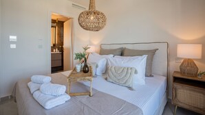 A bedroom with a bed, bedside table, lamp, and a hanging light fixture. - Xenodiki, Amphimatrion Luxe Apt, 750m to the beach, common pool & lovely view (Kalyves)