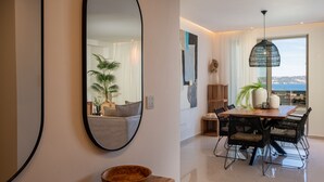 A modern living room with a large mirror, a wooden bowl, and a dining area with a table and chairs. - Xenodiki, Amphimatrion Luxe Apt, 750m to the beach, common pool & lovely view (Kalyves)