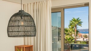A dining area with a wooden table, black wicker chairs, a woven pendant light, and a view of a swimming pool and palm trees. - Xenodiki, Amphimatrion Luxe Apt, 750m to the beach, common pool & lovely view (Kalyves)