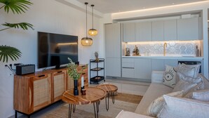 A modern living room with a flat-screen TV, wooden sideboard, and a dining area. - Xenodiki, Amphimatrion Luxe Apt, 750m to the beach, common pool & lovely view (Kalyves)