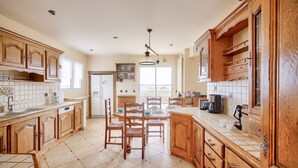A spacious kitchen with wooden cabinets, a dining area with chairs, and a large window providing natural light.
