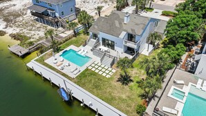 Une maison à deux étages avec une piscine, un quai et un bateau.