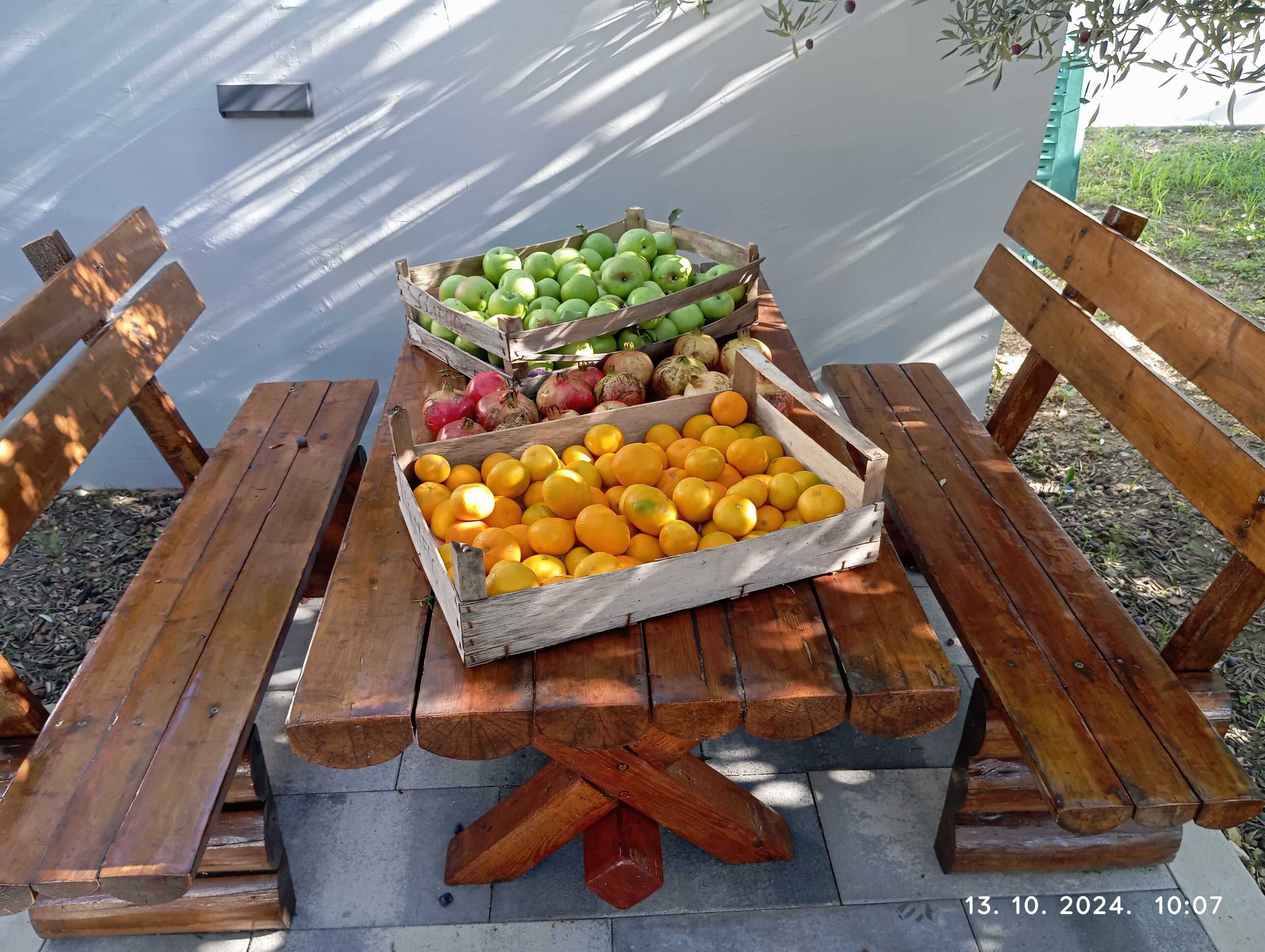 A wooden picnic table with crates of fruits and vegetables.