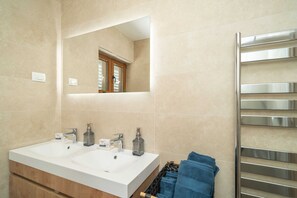 Un bagno con due lavandini, uno specchio e un portasciugamani.