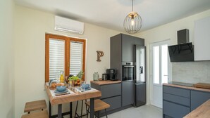 Une cuisine moderne dotée d’un îlot central, d’appareils électroménagers intégrés et d’un luminaire suspendu.