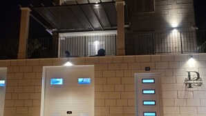 Un bâtiment à la façade en briques, doté d’un porche et de portes de garage éclairées.