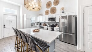 A modern kitchen with white cabinetry, stainless steel appliances, and a central island with bar stools.