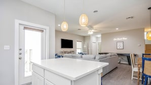 A modern kitchen with white cabinetry, a central island, and pendant lighting. - Coastal Family Escape | Shuffleboard, Heated Pools & Beach Nearby (Corpus Christi)