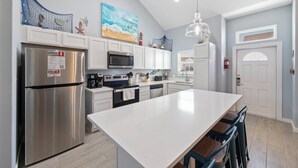 A modern kitchen with white cabinets, stainless steel appliances, and a large island. - Pet-Friendly Coastal Stay | Pools & Waterfront Access (Corpus Christi)