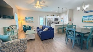 A modern living room with a blue sofa, matching chairs, and a dining table. - Family Beach Getaway | 2 Pools, Splash Pad & Pets Welcome (Corpus Christi)