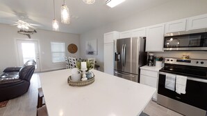 A modern kitchen with stainless steel appliances, a large island, and pendant lighting.