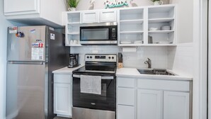 A modern kitchen with stainless steel appliances, white cabinetry, and decorative plants. - Family Getaway | Swim, Slide & Relax w/ Pools & Splash Pad (Corpus Christi)