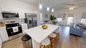 A modern kitchen with white cabinets, stainless steel appliances, and a central island with stools.