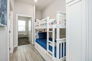 Habitación con literas, suelo de madera, paredes blancas y una ventana.