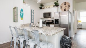 A kitchen with a granite countertop, white cabinets, stainless steel appliances, and a clock on the wall. - Pet-Friendly Beach Escape | Pool Views & Private Patio (Corpus Christi)