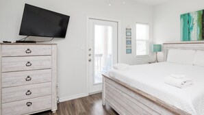 A bedroom with a bed, a dresser, a television, and a window with blinds. - Pet-Friendly Beach Escape | Pool Views & Private Patio (Corpus Christi)