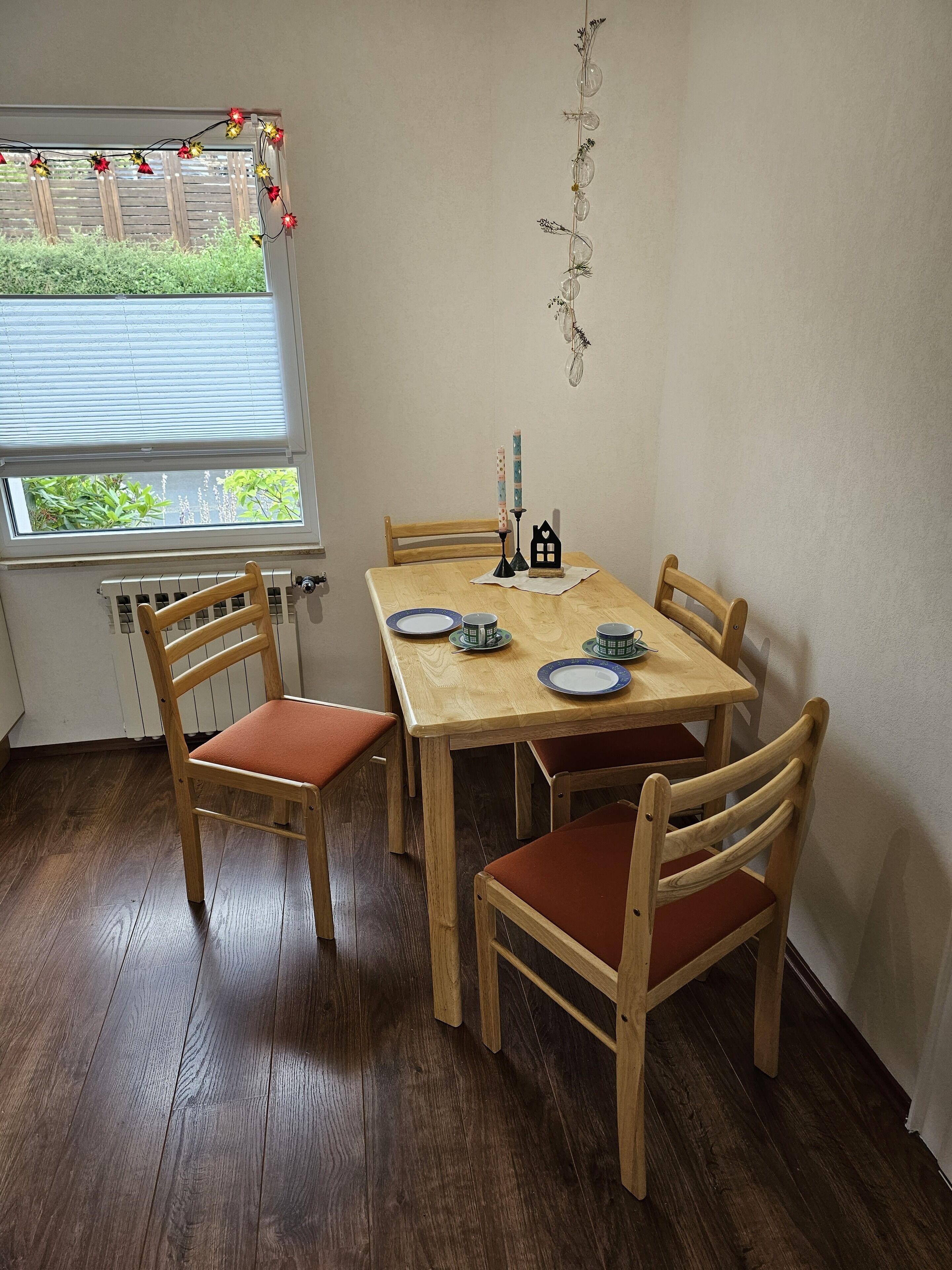 A dining area with a wooden table, six chairs, and a window with blinds.