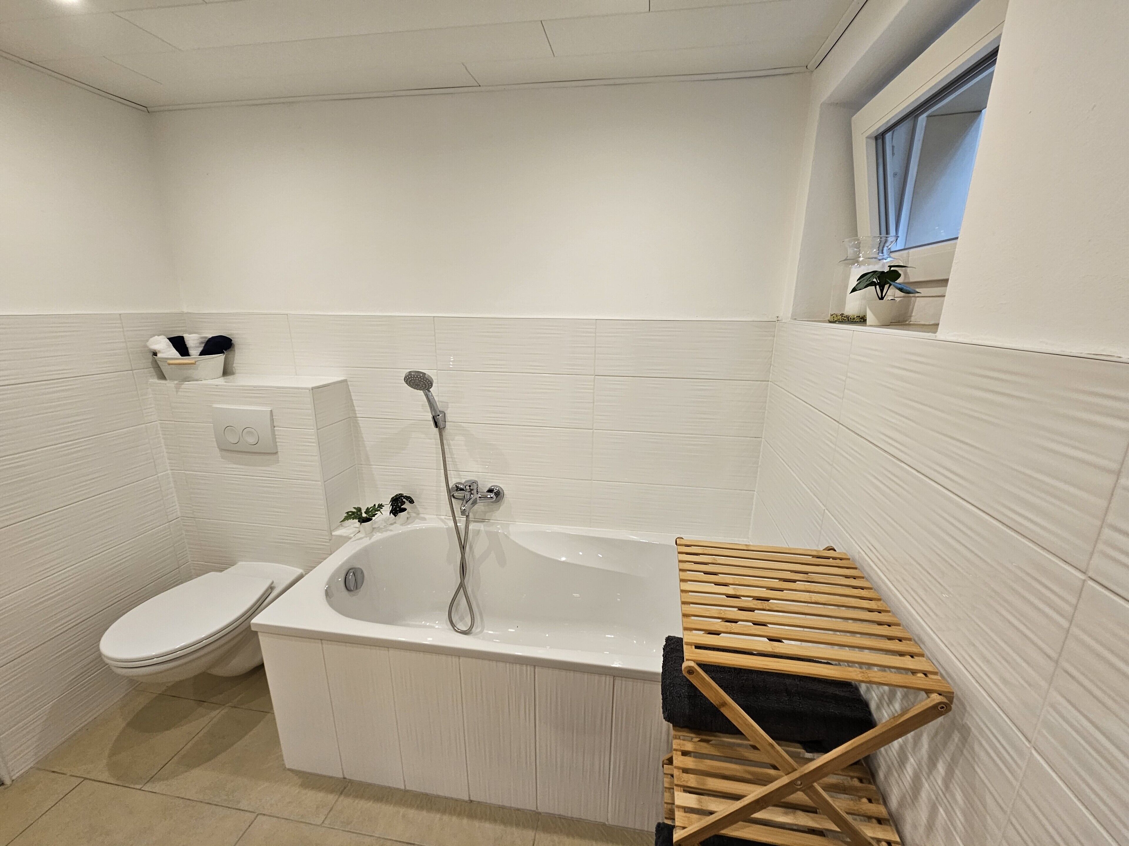 A bathroom with a bathtub, toilet, and a window.