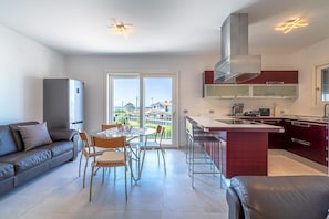 Et moderne køkken med en central ø, et spiseområde med bord og stole, samt en sofa.