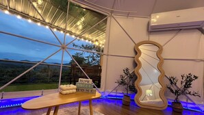 A cozy interior with a wooden table, a decorative mirror, and a view of the outdoors.