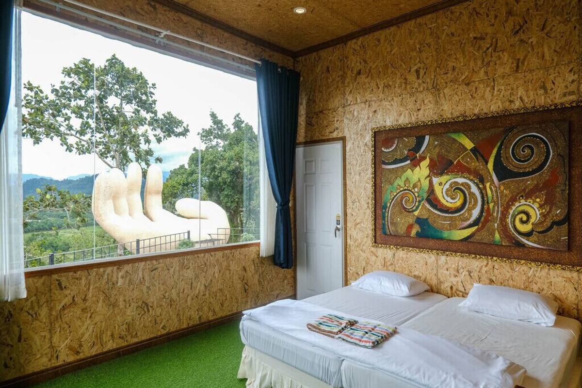 A room with a bed, a window with a view of trees, and a colorful abstract painting on the wall.