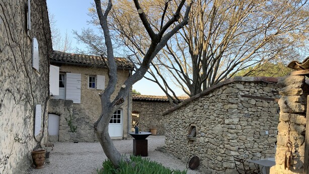 Ein Innenhof mit Steinmauern, einem Baum und einem kleinen Tisch mit Stühlen.