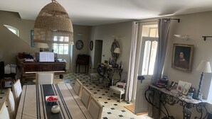 Ein geräumiges Wohnzimmer mit einem Klavier, einem Esstisch und einem großen Fenster.