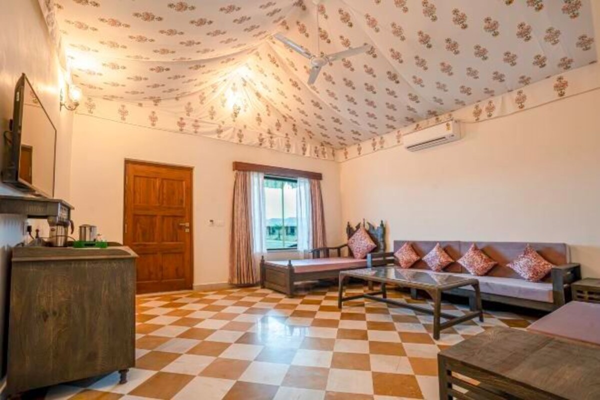 Una habitación con piso a cuadros, un sofá con cojines estampados, un mueble de madera y un ventilador de techo.