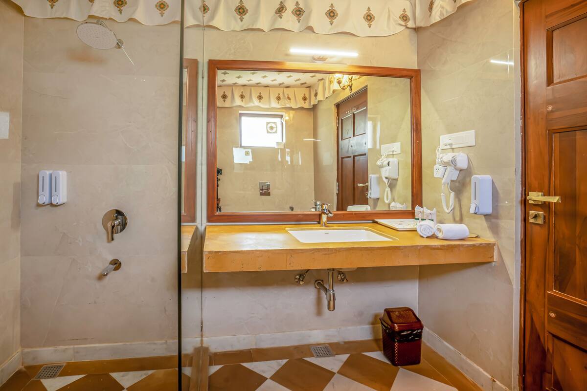 A bathroom with a glass shower enclosure, a sink with a mirror, and a wooden door.