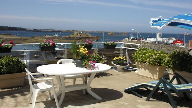 An outdoor patio with a white table and chairs, surrounded by potted plants and flowers. - Maison Ploubazlanec Pour 6 Personnes (Ploubazlanec)