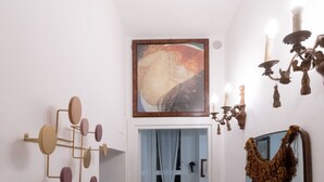 Un corridoio con uno specchio, un lampadario e un quadro appeso al muro.