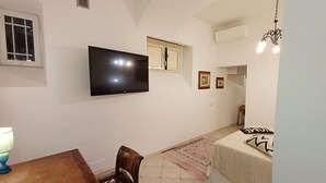 Una camera da letto con un letto, una TV a parete, una finestra e una porta.