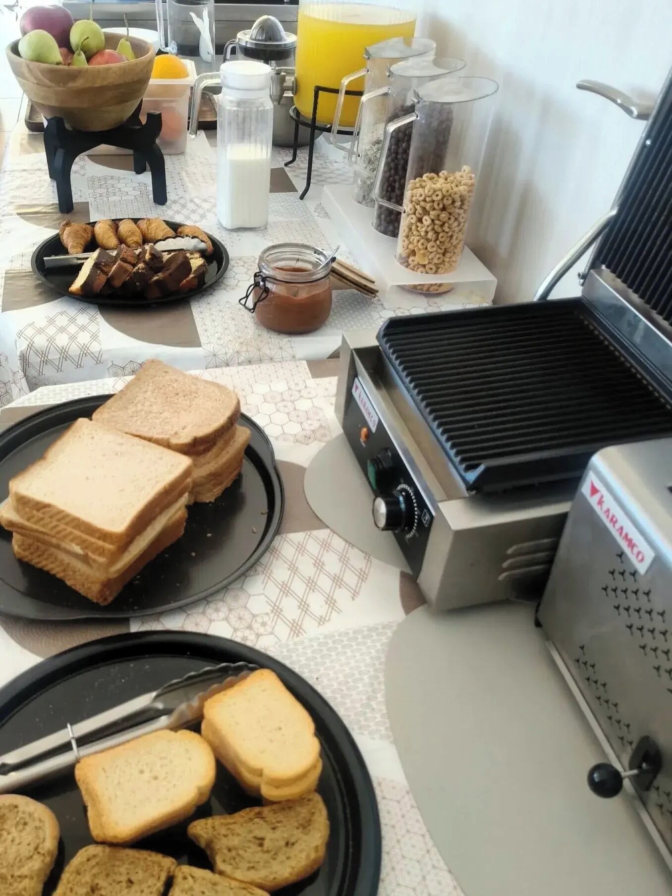 Colazione con pane, pasticcini e una piastra per waffle.