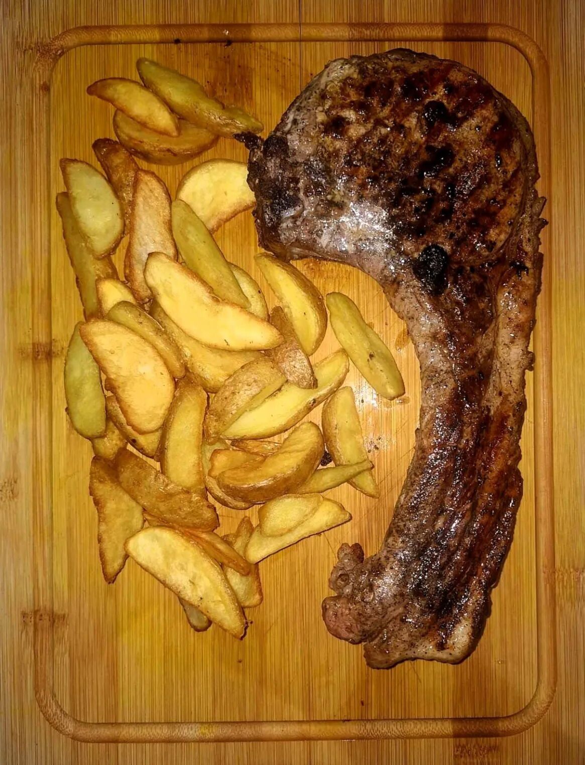 Un bistec con papas fritas sobre una tabla de madera.