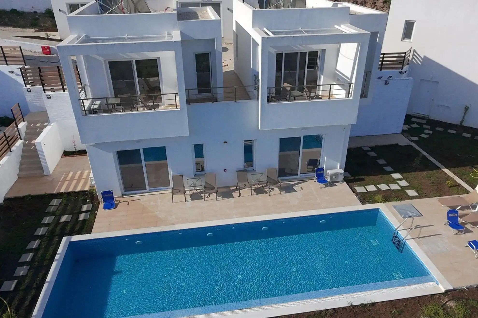 Un edificio moderno de varios pisos con piscina, mobiliario exterior y vista despejada del entorno.