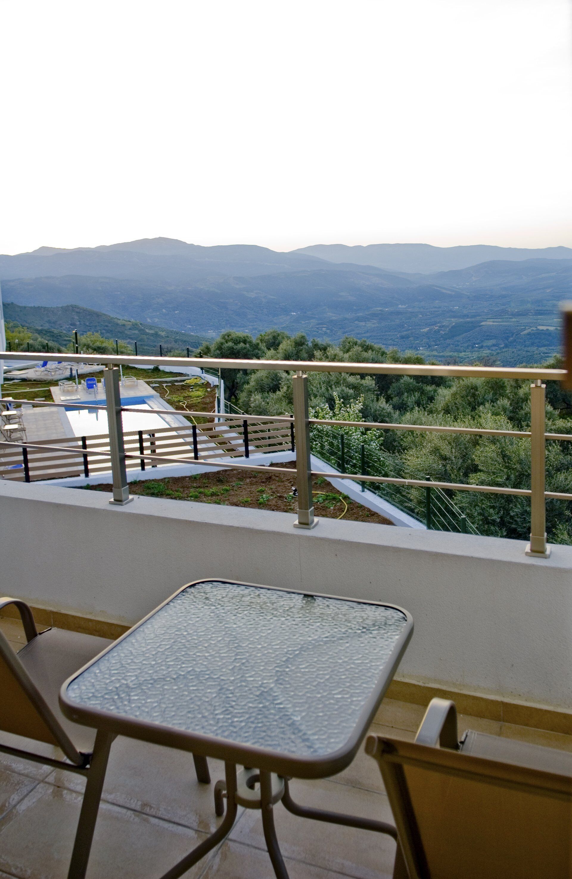 Un balcone con tavolo e sedie, affacciato su un paesaggio montuoso.