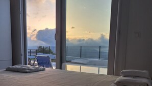 Une chambre d’hôtel avec un grand lit, une chaise et une vue sur le ciel et une clôture à l’extérieur.