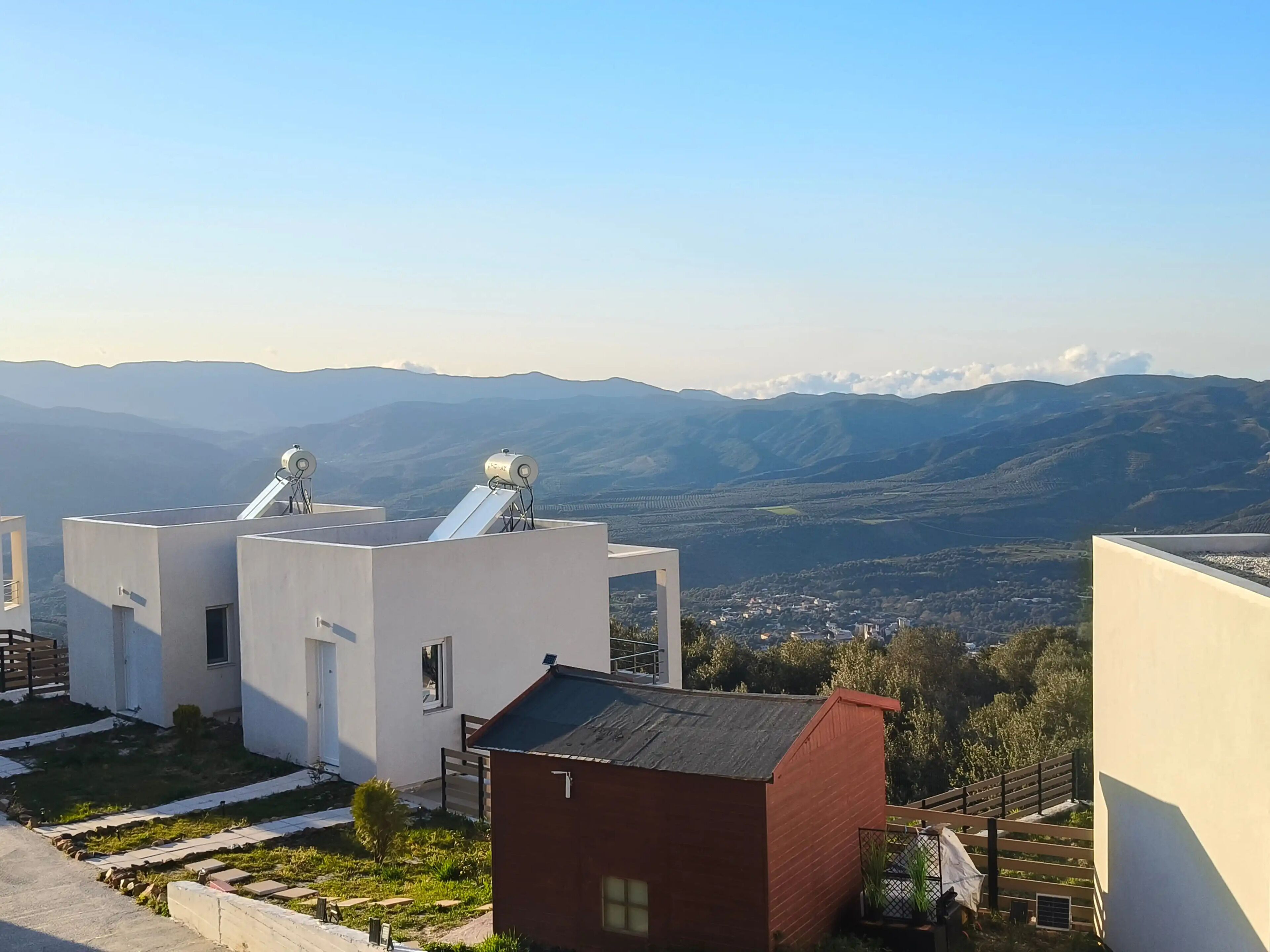 A residential area with modern buildings, solar panels, and a view of distant mountains.