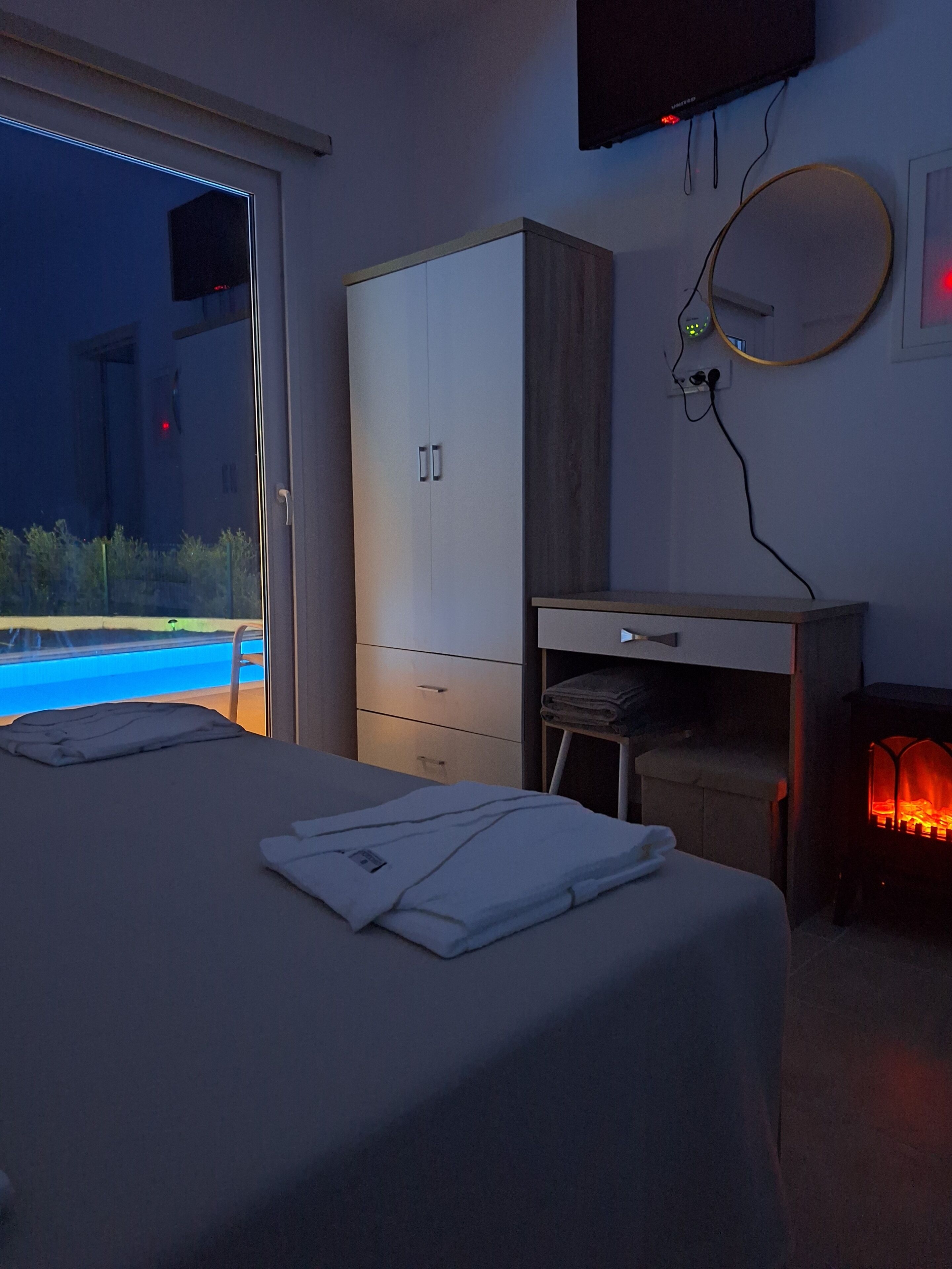 Un dormitorio con cama, armario, escritorio, chimenea y vista a una piscina.