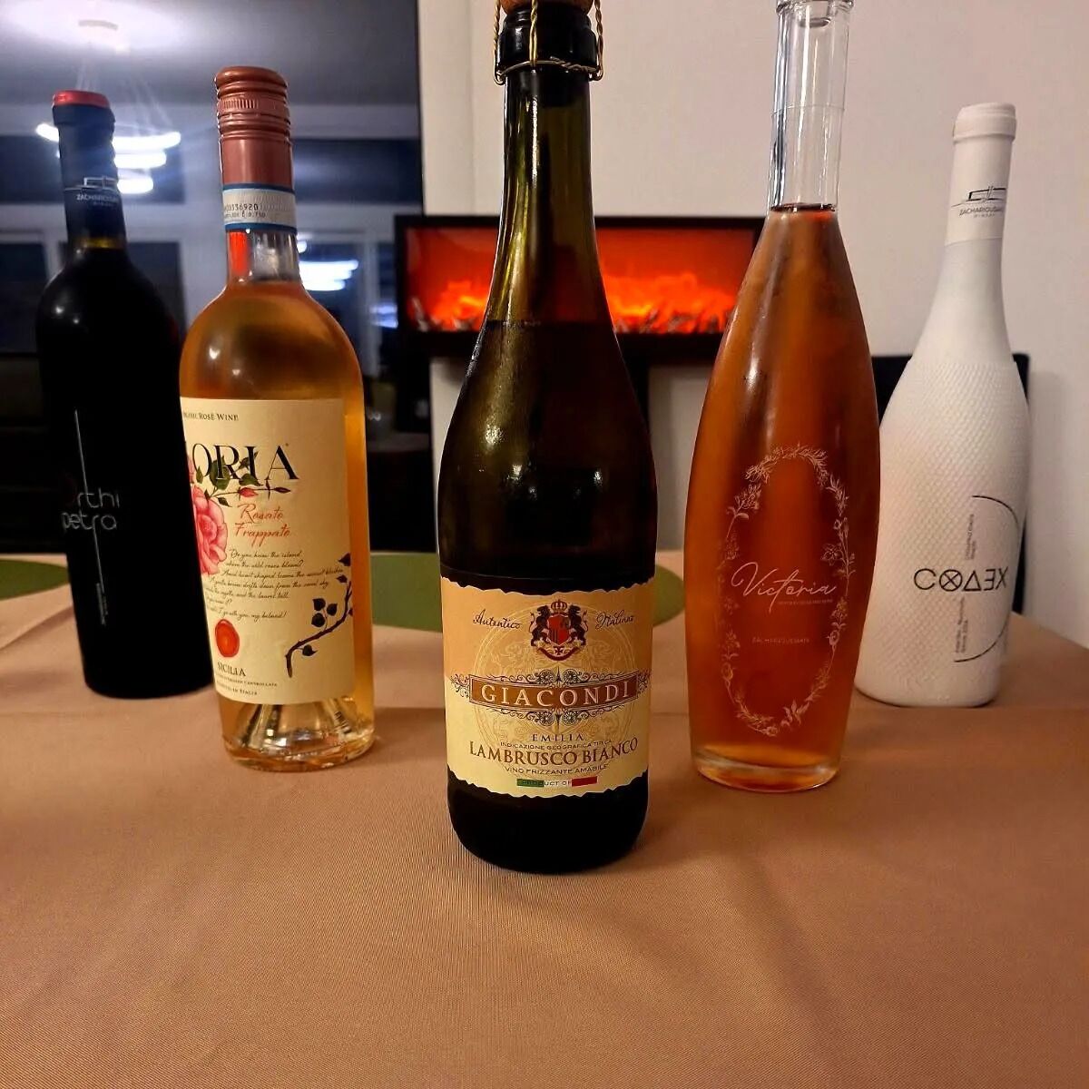 Four bottles of wine on a table with a television in the background.