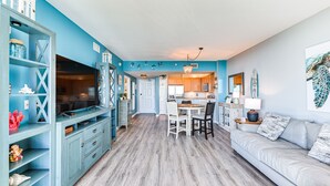 A modern kitchen with a dining area, a living room with a sofa, and a TV. - Palms of Destin Resort Condo w/ Private Balcony! (Destin)